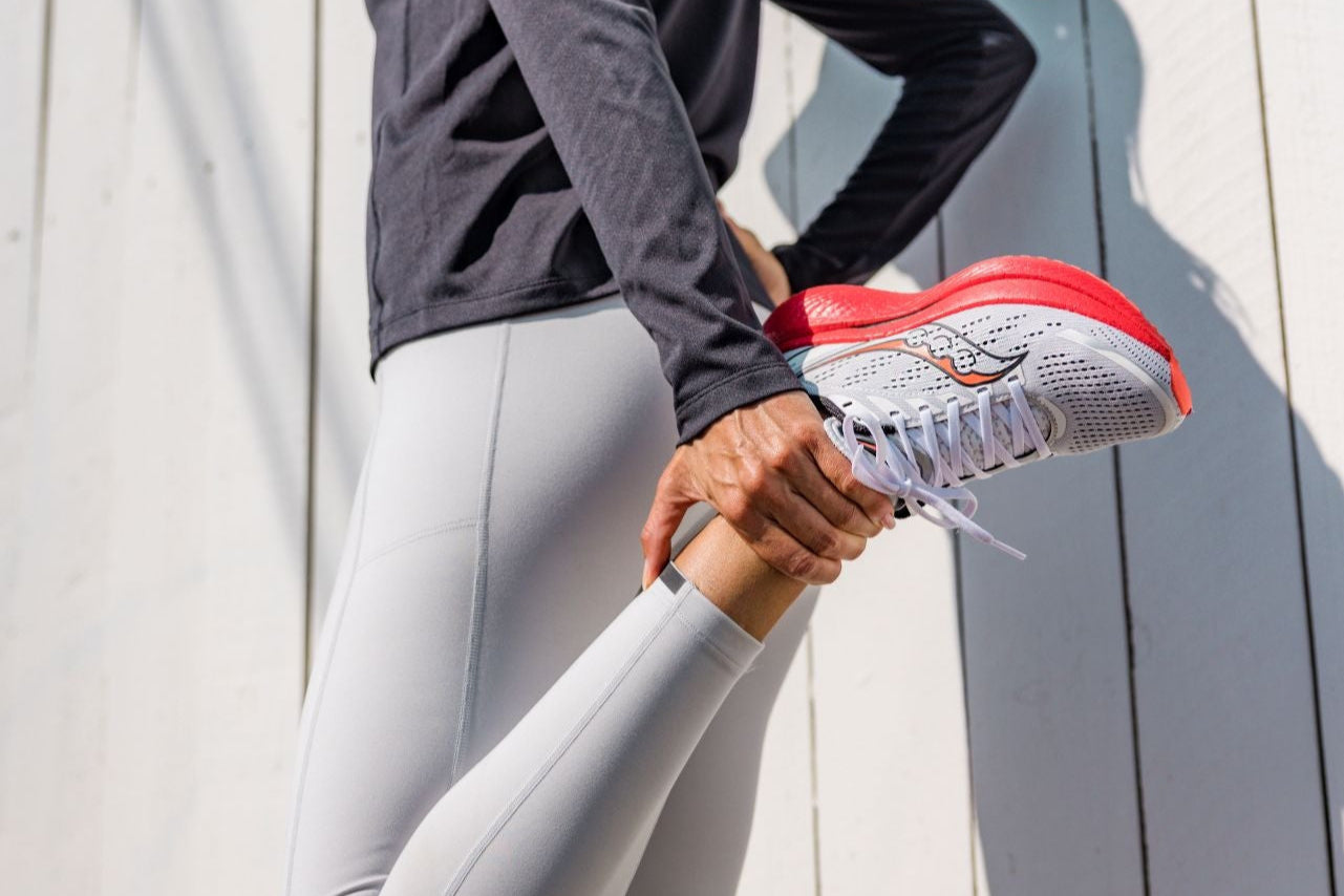 Person wearing gray athletic outfit and running shoes against a light wooden background