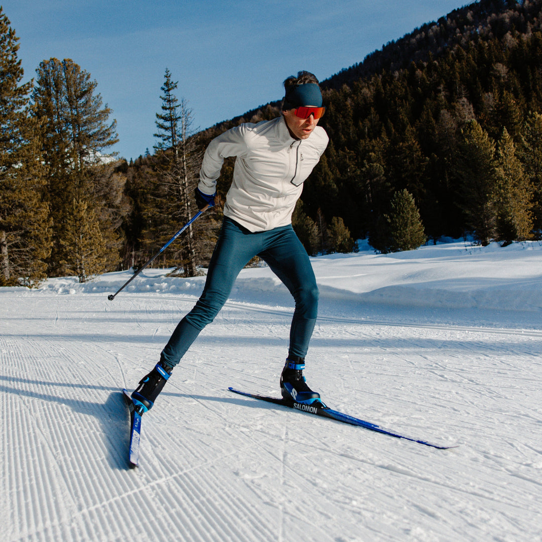 Person cross-country skiing on a snowy landscape with trees in the background