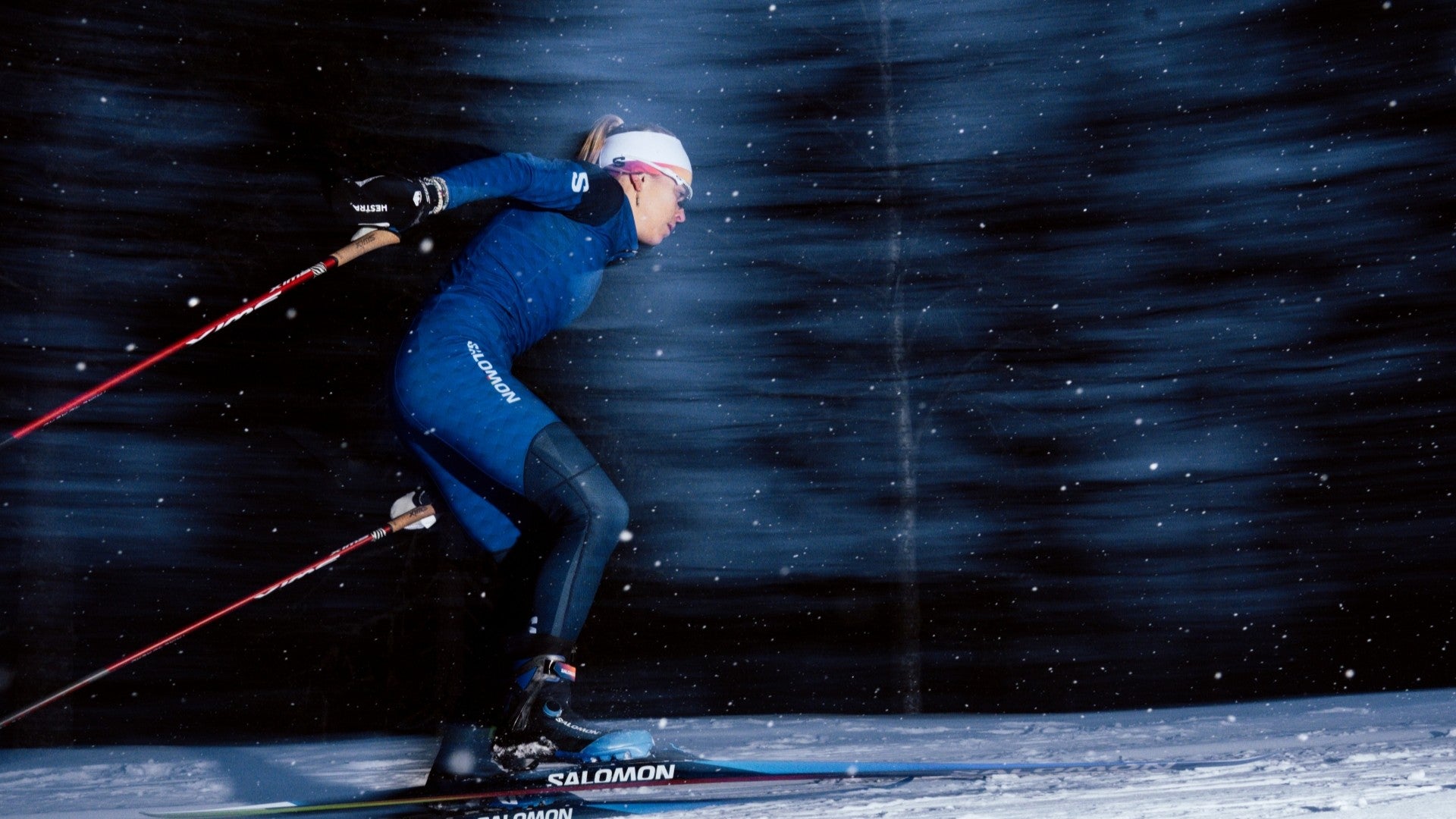 Skiier in blue outfit skiing at night