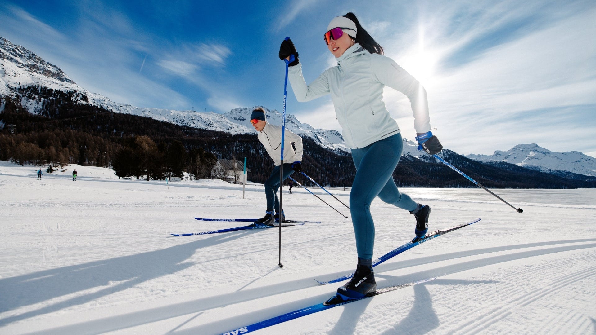 Person cross-country skiing on a snowy landscape with mountains in the background
