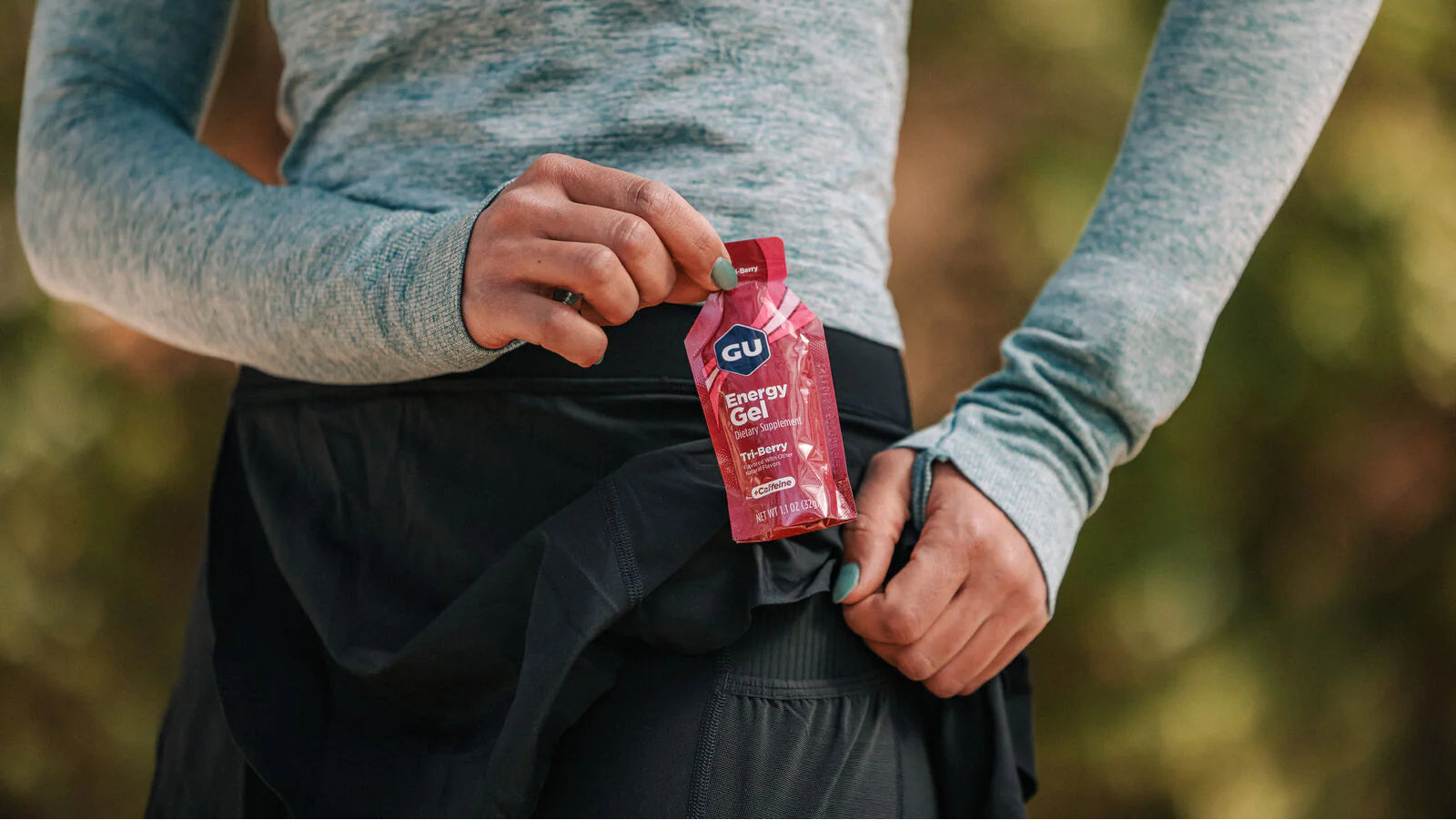 Person holding a GU Energy Gel pack outdoors