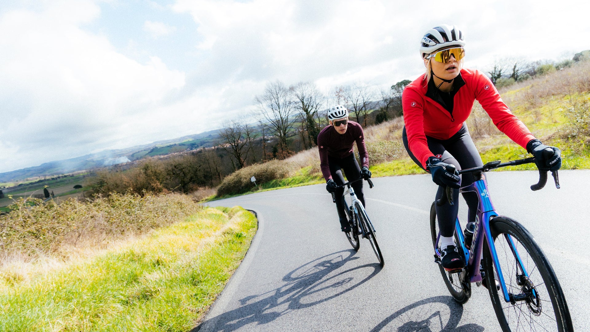Two cyclists riding on a road with a scenic background