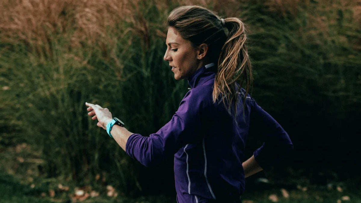 Woman in a purple jacket standing in a grassy field