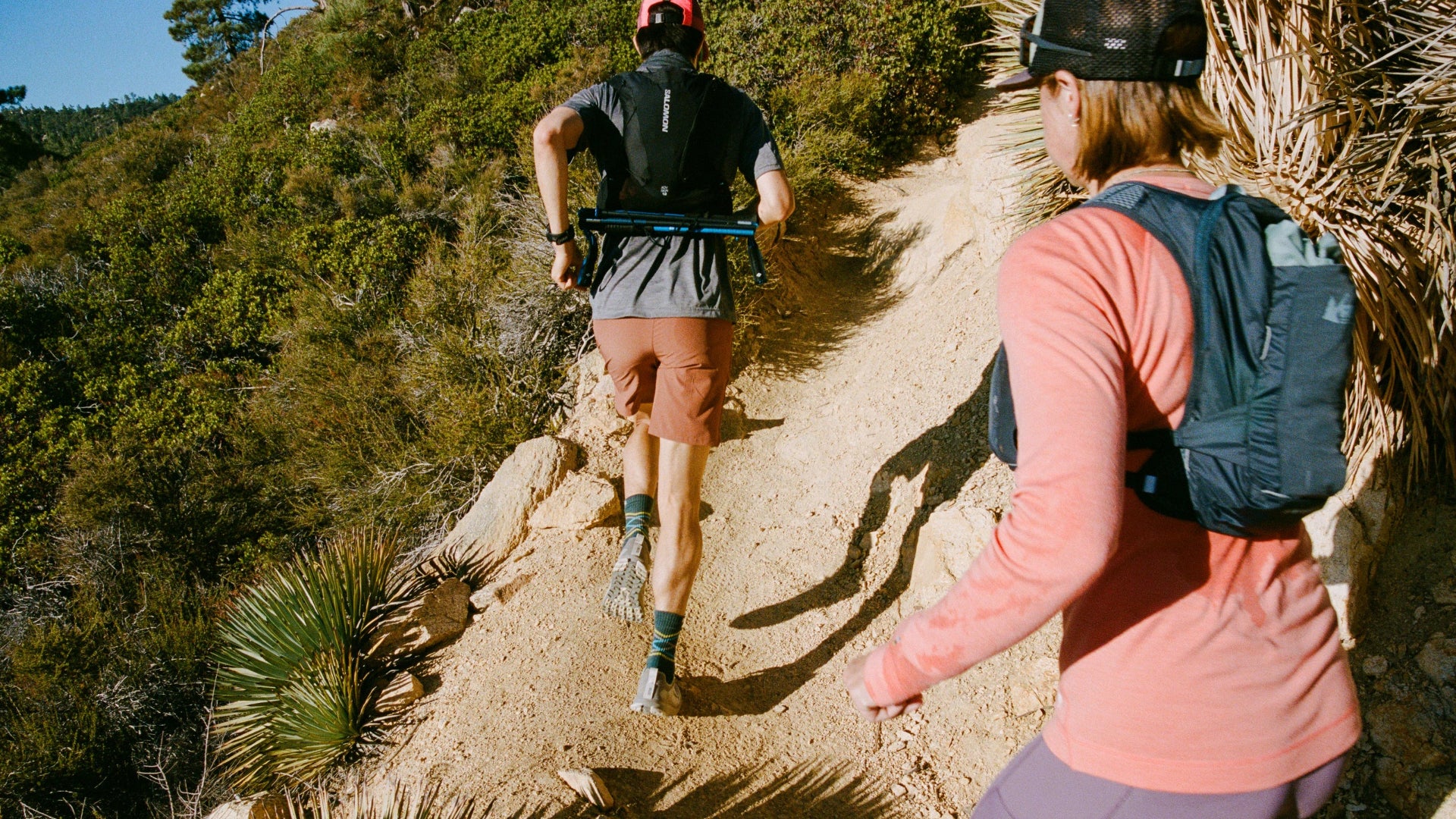 Two people hiking on a trail with backpacks in a natural setting