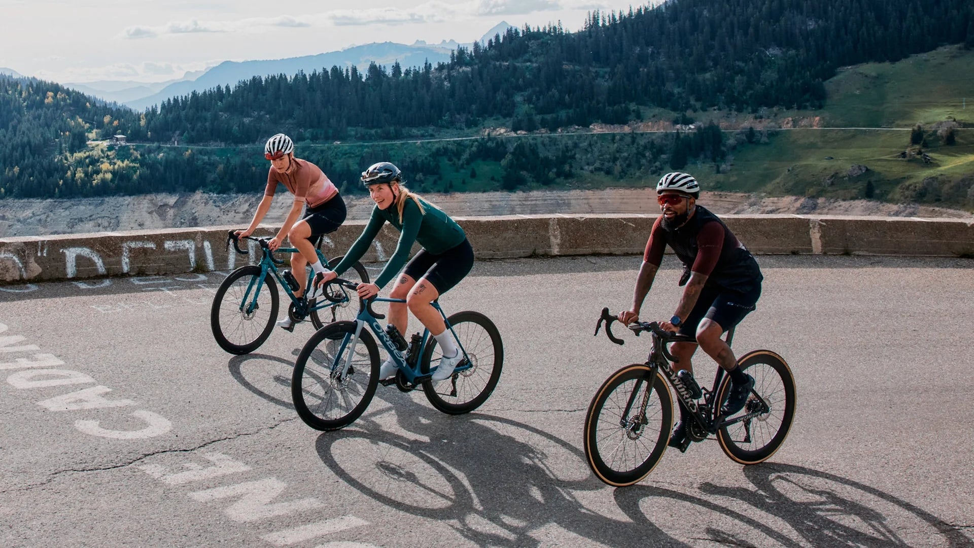 Three cyclists riding on a road with a scenic background